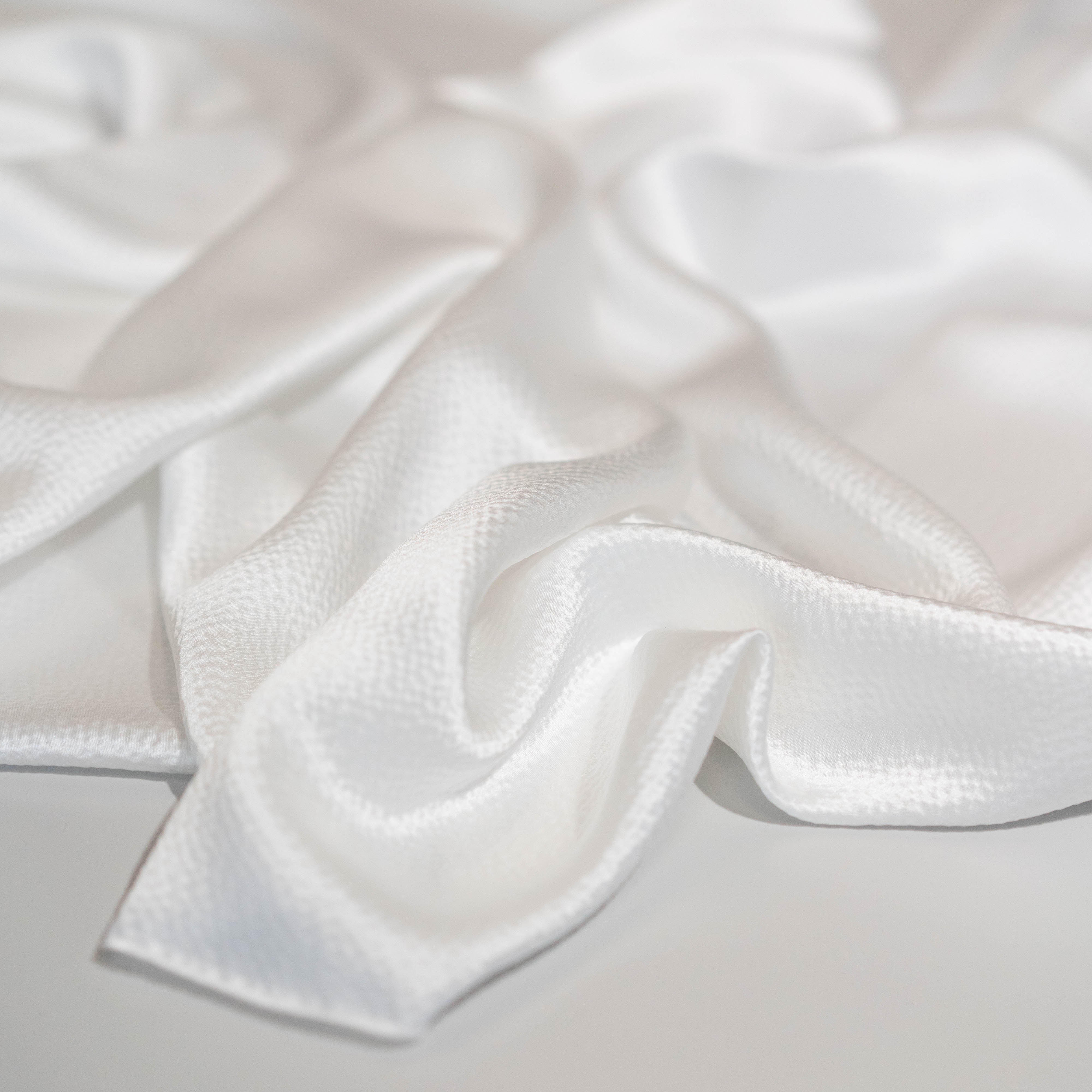 Close-up of textured hammered silk satin fabric in ivory colour, perfect for shirts, skirts and dresses, fashion and bridal