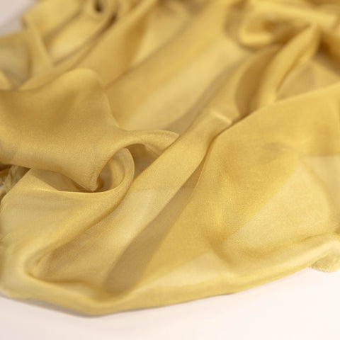 Close-up of yellow gold silk chiffon fabric, pure silk, 100% silk, for ethereal draped dresses and gowns, high-fashion and special occasion wear.