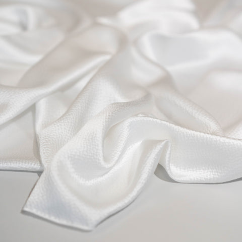 Close-up of textured hammered silk satin fabric in ivory colour, perfect for shirts, skirts and dresses, fashion and bridal